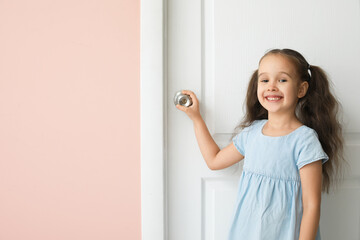 Fototapeta na wymiar Cute little girl standing near closed door