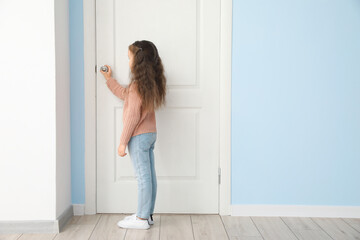 Cute little girl standing near closed door