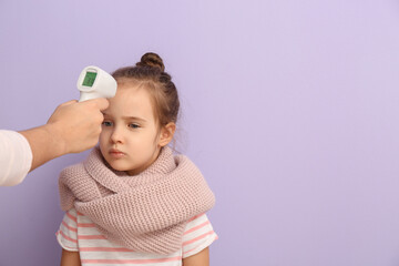 Woman measuring temperature of her little daughter ill with flu against color background