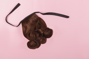 A brown hairpiece on the pink background. A ponytail chignon, hair extension, quick easy hair style...