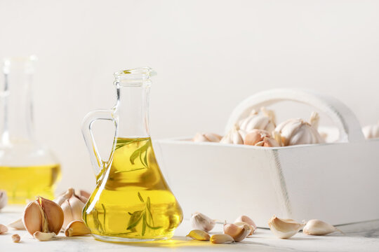 Jug of garlic oil on light background