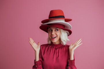 Funny woman wearing many hats  posing on pink background. Model looking aside. Fashion, sale,...