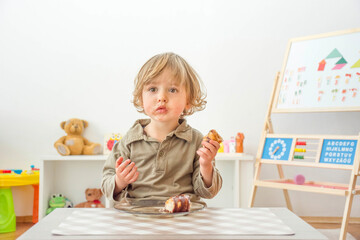 Cute happy child boy having fun eating chocolate cake at home. Chocolate, sweets and sugar, unhealthy food for children conceptual photo