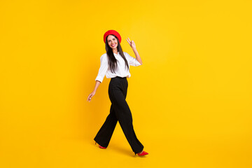 Fototapeta na wymiar Full body photo of cheerful nice lady make v-sign hello walk empty space isolated on bright yellow color background