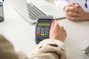 Patient paying for consultation in clinic via terminal, closeup