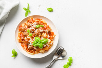 Pasta fettuccine with meatballs and tomato sauce on a white background. View from above. Space for...