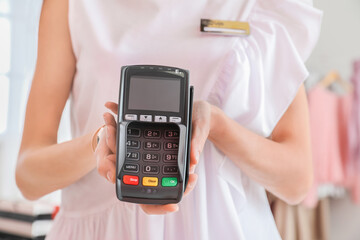 Seller with payment terminal in modern shop, closeup