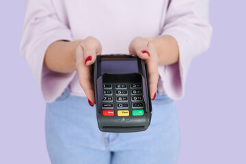 Young woman with payment terminal on color background, closeup