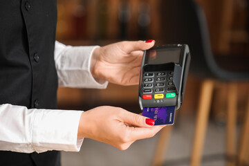 Waiter with payment terminal and credit card in cafe, closeup