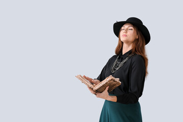 Female fortune teller with spell book on light background
