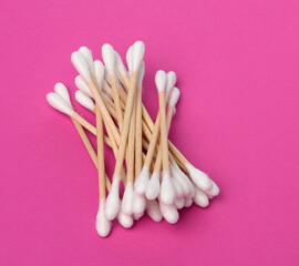 wooden sticks with white cotton wool for the ears on a pink background, hygiene product