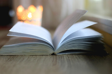 Open book and lit candle on a table. Selective focus.