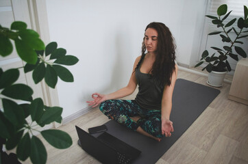 girl meditates at home on the rug with a computer. online meditation