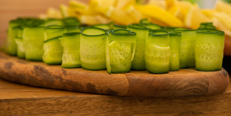 Rolled cucumbers slices on a wooden plate
