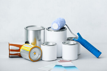 Cans of paints, roller, palette samples on white background