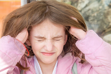 cute beautiful natural teen girl presses her hands to her temples because she has a headache