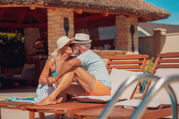 Senior couple kissing by the swimming pool - Powered by Adobe