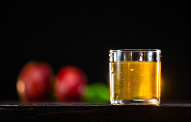 Glass of apple juice and red apples on wooden background. Close up