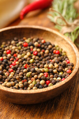 Bowl with mixed peppercorns on table, closeup