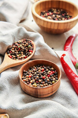 Bowls and spoon with mixed peppercorns on fabric background