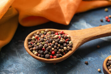 Spoon with mixed peppercorns on color background, closeup