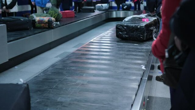 People pick up their belongings on a conveyor belt at the airport at baggage claim.
Suitcases move along a conveyor belt at the airport. Baggage claim at the airport. 