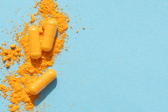 orange curcumin turmeric pills with powder and shadow