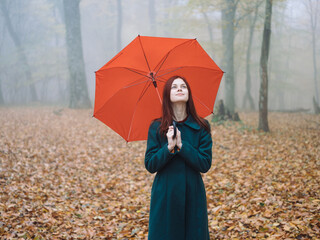 Pretty woman red umbrella walk in autumn in the forest with fog yellow leaves