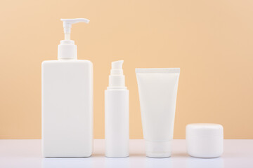 Set of cosmetic for skin care in white tubes on white table against bright beige background....