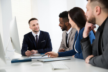 Group of multi-ethnic business people sitting around the office desk and discussing the project