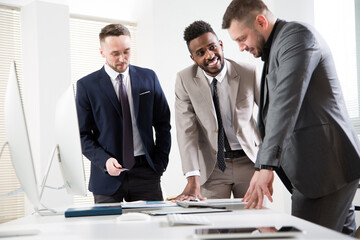 Businessmen standing around the office desk and discussing the project