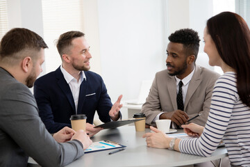 Group of multi-ethnic business people sitting around the office desk and discussing the project