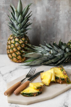 Board with slices of fresh pineapple on table