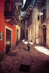 Fototapeta na wymiar Little boy wandering in the empty streets of the little village of Intragna, shot in Centovalli, Ticino, Switzerland