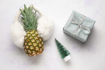 Pineapple with ear warmers, fir tree and gift box on white background