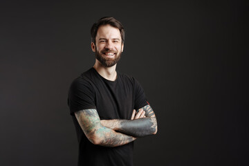 Bearded brunette man with tattoo laughing and looking at camera