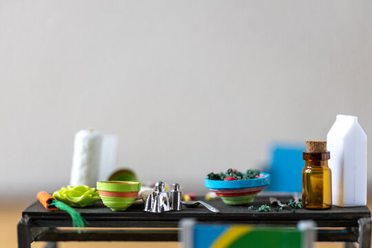 Dinner table in a doll house. Miniature paper bowls,  silver cutlery, paper towel. Room for copy.