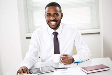 Happy african american businessman smiling at camera in office