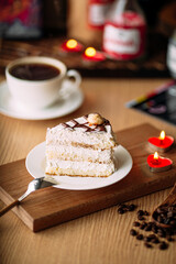 Slice of creamy cake on decorated table with coffee