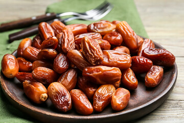 Plate with sweet dried dates on wooden background, closeup