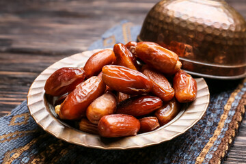 Plate with sweet dried dates on wooden background, closeup