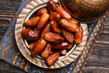 Plate with sweet dried dates on wooden background, closeup