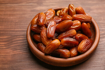 Plate with sweet dried dates on wooden background, closeup