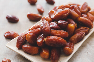 Plate with sweet dried dates on light background, closeup