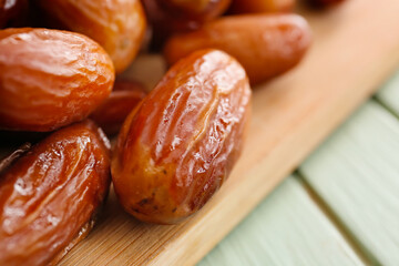 Board with sweet dried dates on color wooden background, closeup