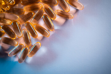 handful of golden fish oil capsules omega 3 vitamins on purple background