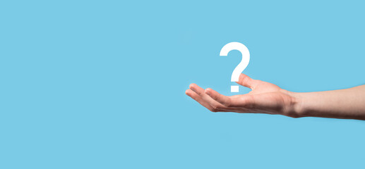 Male hand holding question mark icon on blue background.Banner with copy space. Place for text.