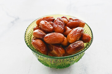 Bowl with sweet dried dates on light background, closeup
