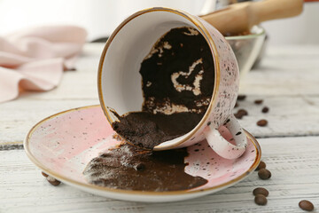 Cup with spent coffee grounds for fortune telling on wooden background