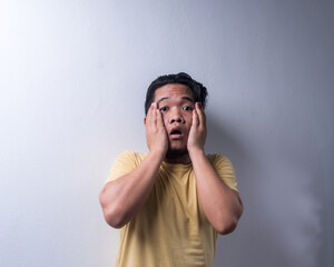 Face reaction, Asian young man portrait of face expression, shocked, thrilled, scared, surprised, with covered face with hand. Isolated, selective focus, copy space